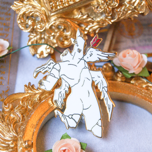 Enamel pin depicting a fallen angel statue, who has lost their limbs and head. A red arrow is through their chest. Behind are golden frames and miniature roses.  