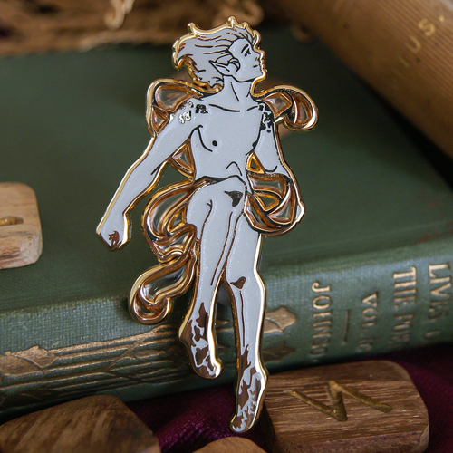 Pin depicting the spirit Ariel; a floating, androgynous figure surrounded by a billowing cloak. The background is a stack of books. 